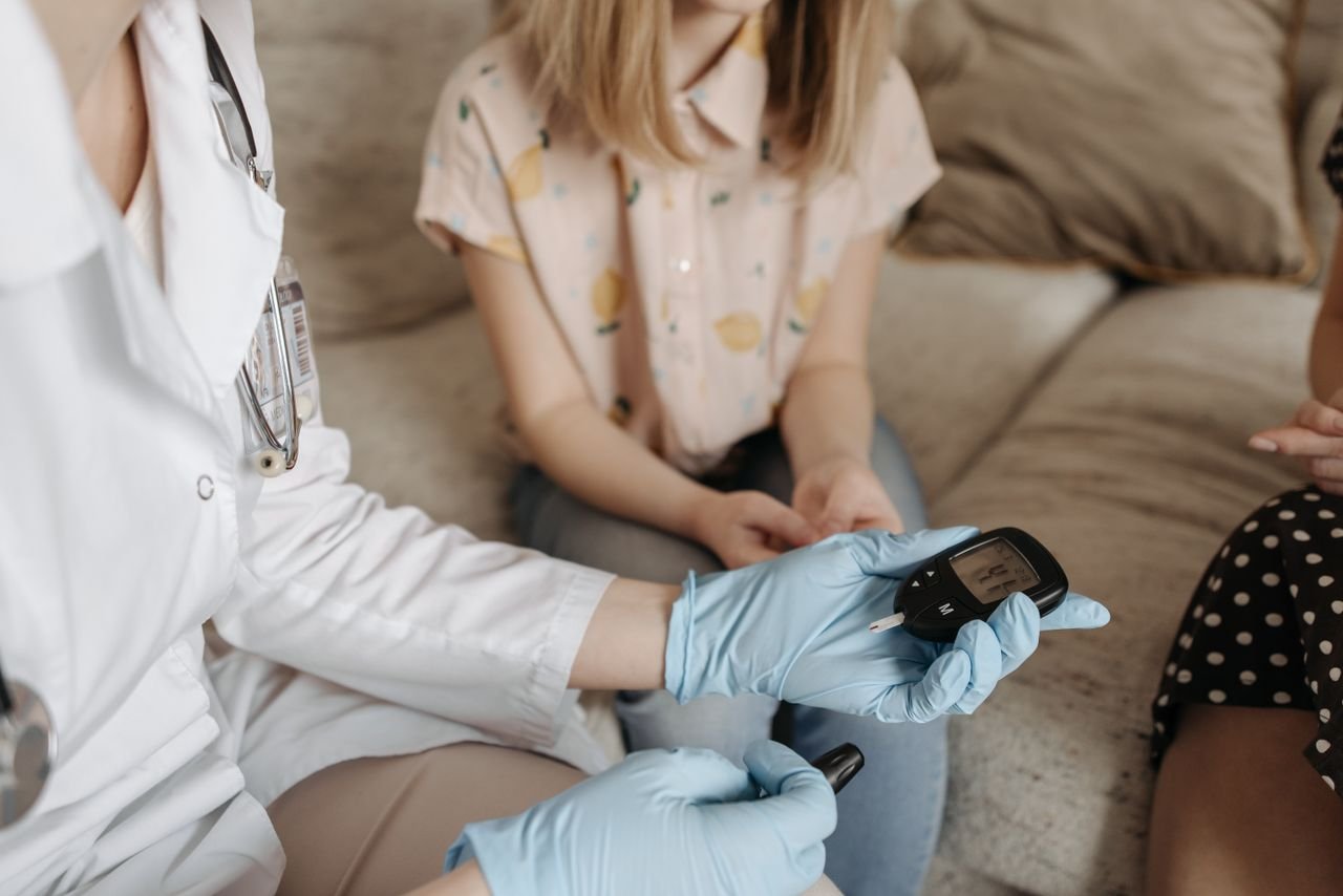 Home Doctor using a glucose meter to check a patient's blood sugar during a medical consultation.